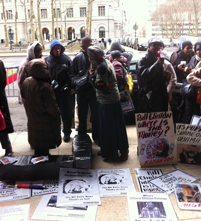 2015, activistes haïtiens manifestant devant le quartier général d'Hillary Clinton à Brooklyn. Entre autres, on peut lire sur une des pancartes "Bill Clinton, où est passé l'argent ?".